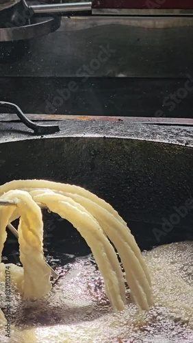 Close-up vertical video of unrecognizable person making harian churros in oil 3