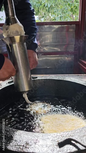 Close-up vertical video of unrecognizable person making harian churros in oil