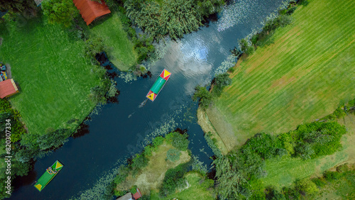Sunny day at Xochimilco canal with two boats sailing peacefully through the waters amidst lush green fields and trees
