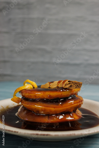 Vertical image of sopaipillas pasadas, topped with an orange peel. on a light blue wooden table on a rustic white wall background. Typical Chilean food
