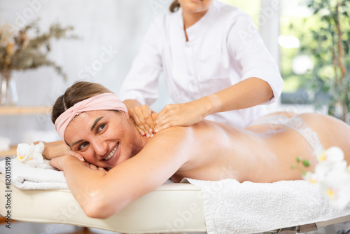 Young woman enjoying deep tissue back and shoulders massage to release muscle tension and provide therapeutic relief from professional masseuse..