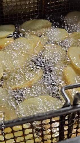 vertical video of deep fryer with crispy French fries in oil to accompany grilled meat 2