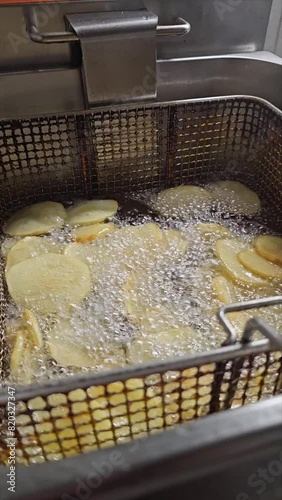 vertical video of deep fryer with crispy French fries in oil to accompany grilled meat