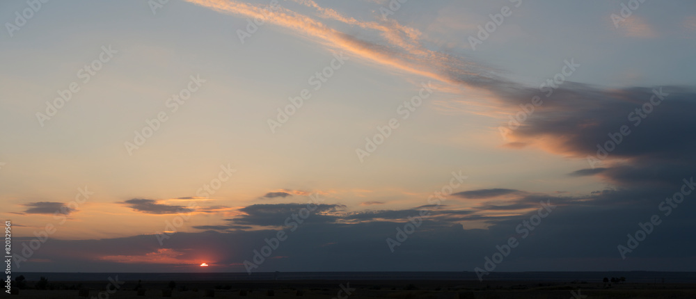 Fototapeta premium Landscape with bloody sunset. Panorama. Tragic gloomy sky. The last flashes of the sun on the storm clouds.