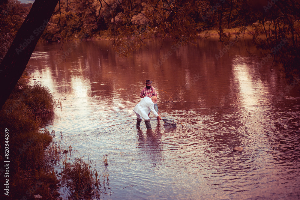 Portrait of cheerful senior man fishing. Grandfather and son fishermans. Young man and an old man fishing for spinnings on the river or lake.