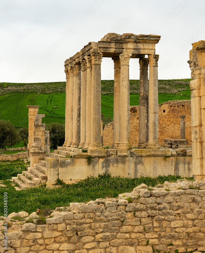 Well-preserved remnants of temple of Juno Caelestis with towering columns at ruins of ancient Roman settlement of Dougga in northern Tunisia on cloudy spring day