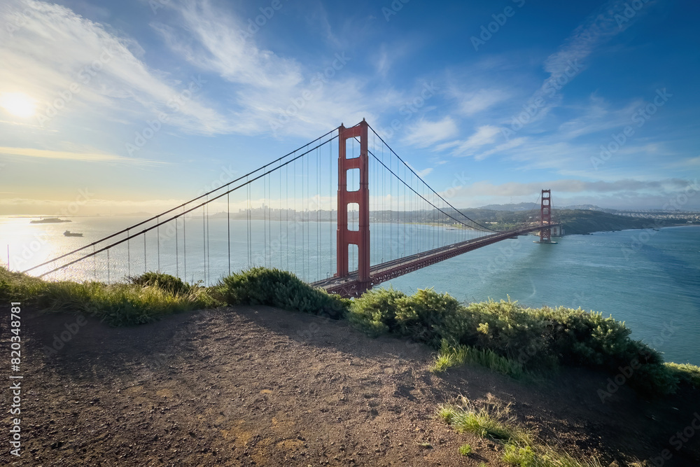 Scenic view of Golden Gate Bridge and cityscape of San Francisco, California, USA at sunrise against blue sky with clouds Scenic view of Golden Gate Bridge and cityscape of San Francisco, California, USA at sunrise against blue sky with clouds