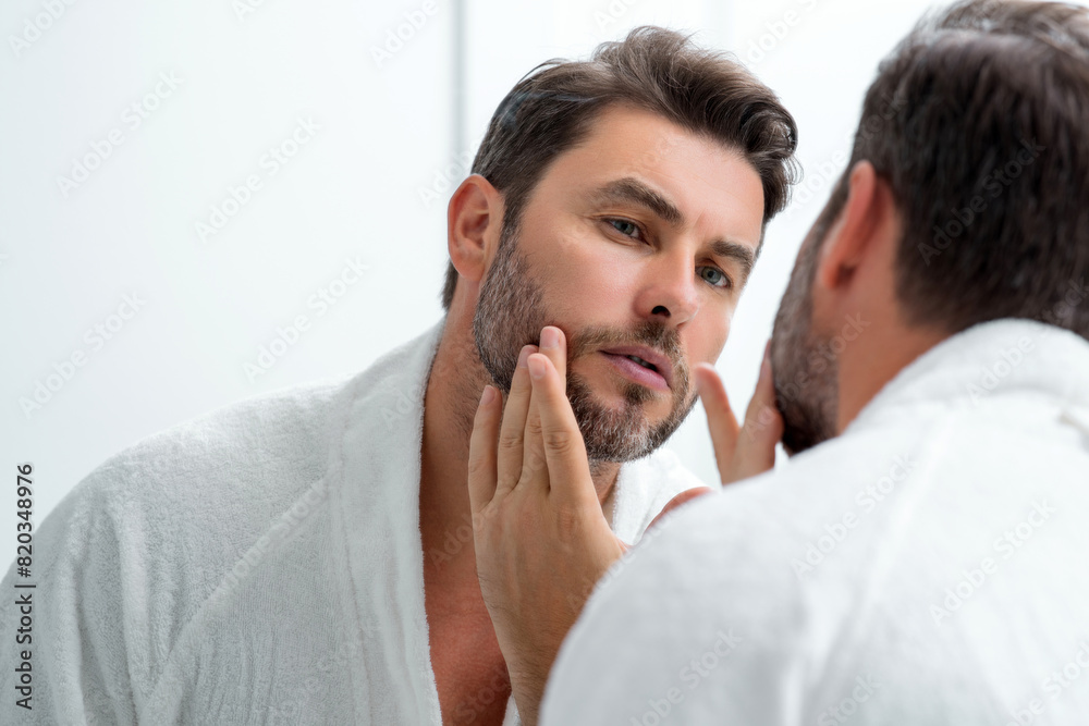 Male beauty cosmetics, beauty and skincare. Morning healthcare and hygiene for man. Perfect beauty skin. Handsome millennial man after shower apply nourishing facial cream or mask on skin. Male beauty cosmetics, beauty and skincare. Morning healthcare and hygiene for man. Perfect beauty skin. Handsome millennial man after shower apply nourishing facial cream or mask on skin.