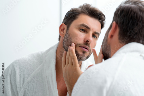 Male beauty cosmetics, beauty and skincare. Morning healthcare and hygiene for man. Perfect beauty skin. Handsome millennial man after shower apply nourishing facial cream or mask on skin.