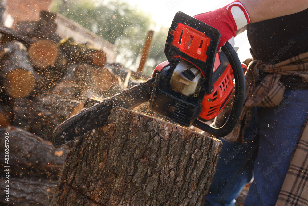 Man sawing wooden log outdoors, closeup view