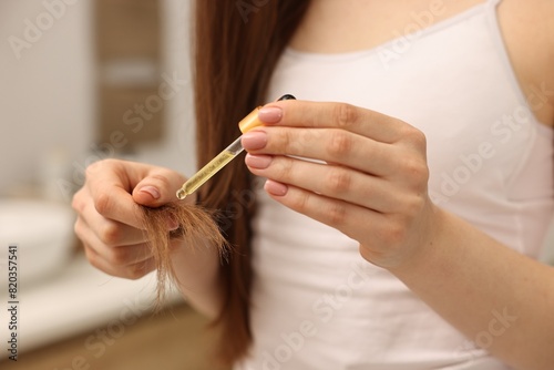 Woman applying oil hair mask indoors  closeup