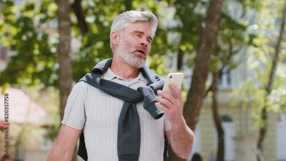 Bearded mature man using smartphone typing browsing, loses becoming surprised sudden lottery results, bad news, fortune loss, fail. Tourist guy standing in urban city street outdoors. Town lifestyles. Bearded mature man using smartphone typing browsing, loses becoming surprised sudden lottery results, bad news, fortune loss, fail. Tourist guy standing in urban city street outdoors. Town lifestyles.