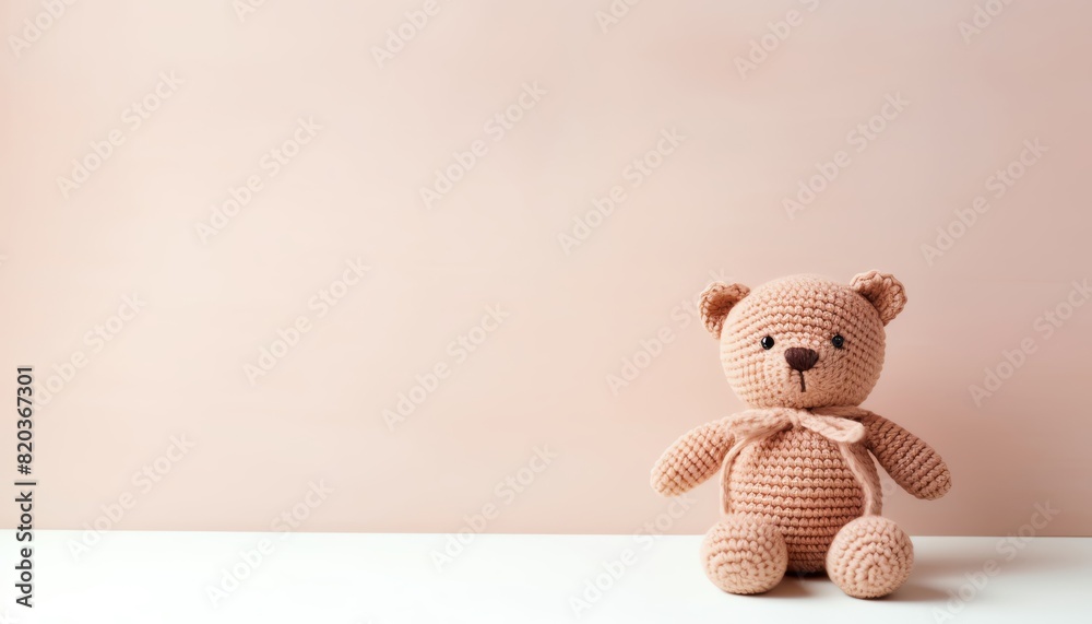 Cute little teddy bear sitting on white table against beige background. Cute little teddy bear sitting on white table against beige background.
