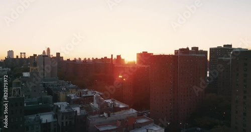 Urban neighborhood with residential buildings in New York City, illuminated by the rays of the rising sun. Drone shot.