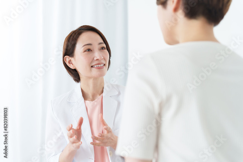 病院で診察する女性医師と患者（美容医療）