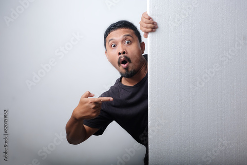 man peeking behind blank sign