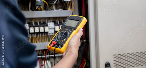 Engineer testing electrical system Using a multimeter to measure the current at the control cabinet.