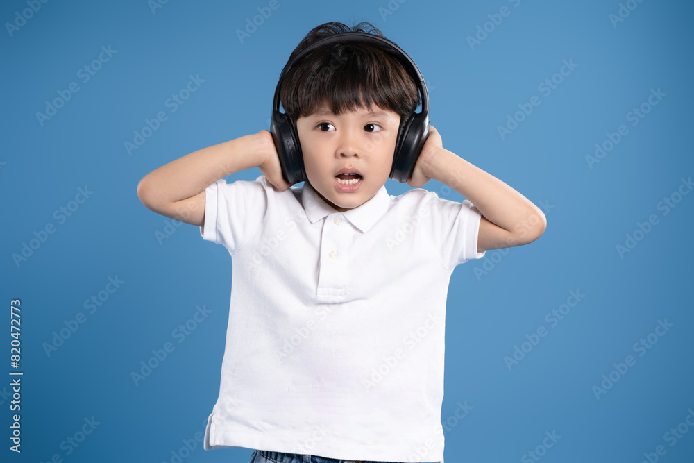 Portrait of asian boy wearing headphones and posing on blue background Portrait of asian boy wearing headphones and posing on blue background