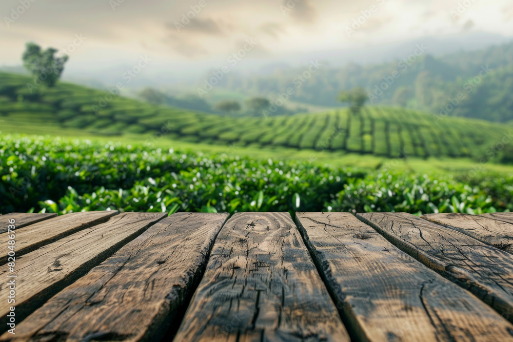 Naklejka premium A wooden desk top with blurred background of tea plantation. Good for background 