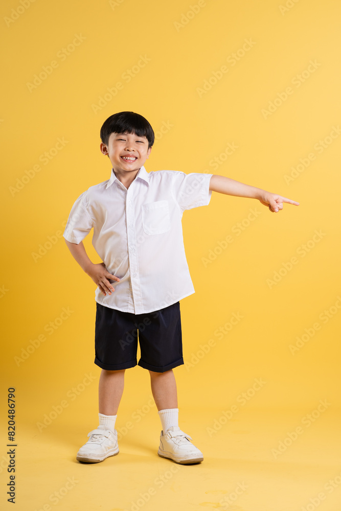 Portrait of adorable asian boy posing on yellow background Portrait of adorable asian boy posing on yellow background