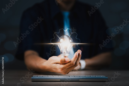 A person is holding a light bulb in their hand, with the bulb glowing brightly