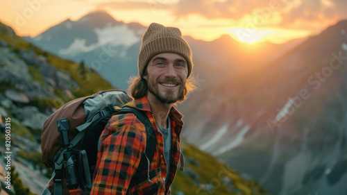 Cheerful man with a backpack standing against beautiful mountain landscape at sunrise © boxstock production