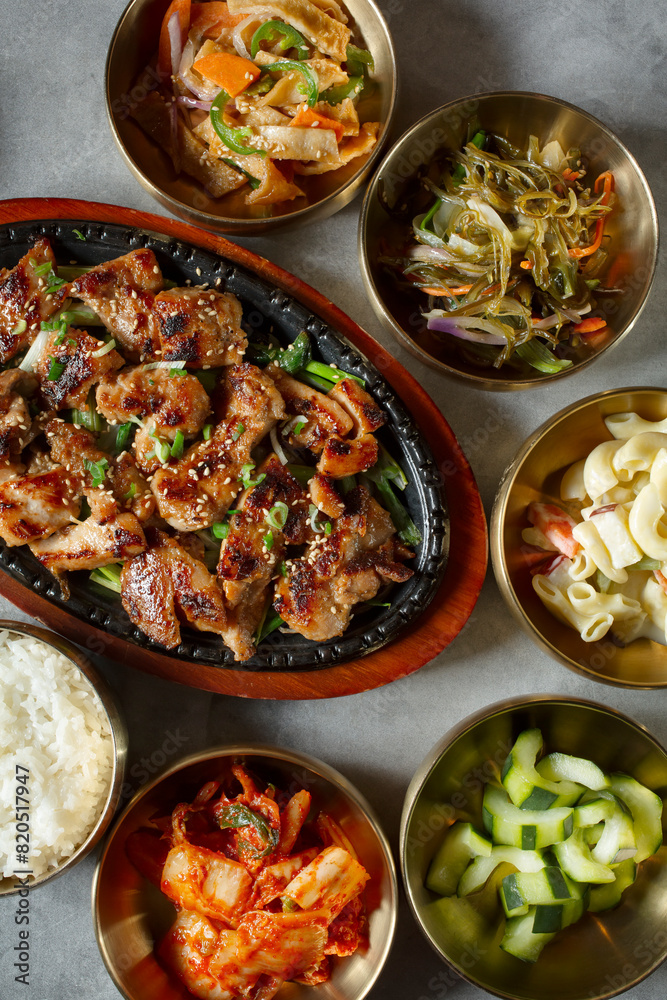A top down view of a skillet plate of chicken bulgogi, among several banchan bowls. A top down view of a skillet plate of chicken bulgogi, among several banchan bowls.