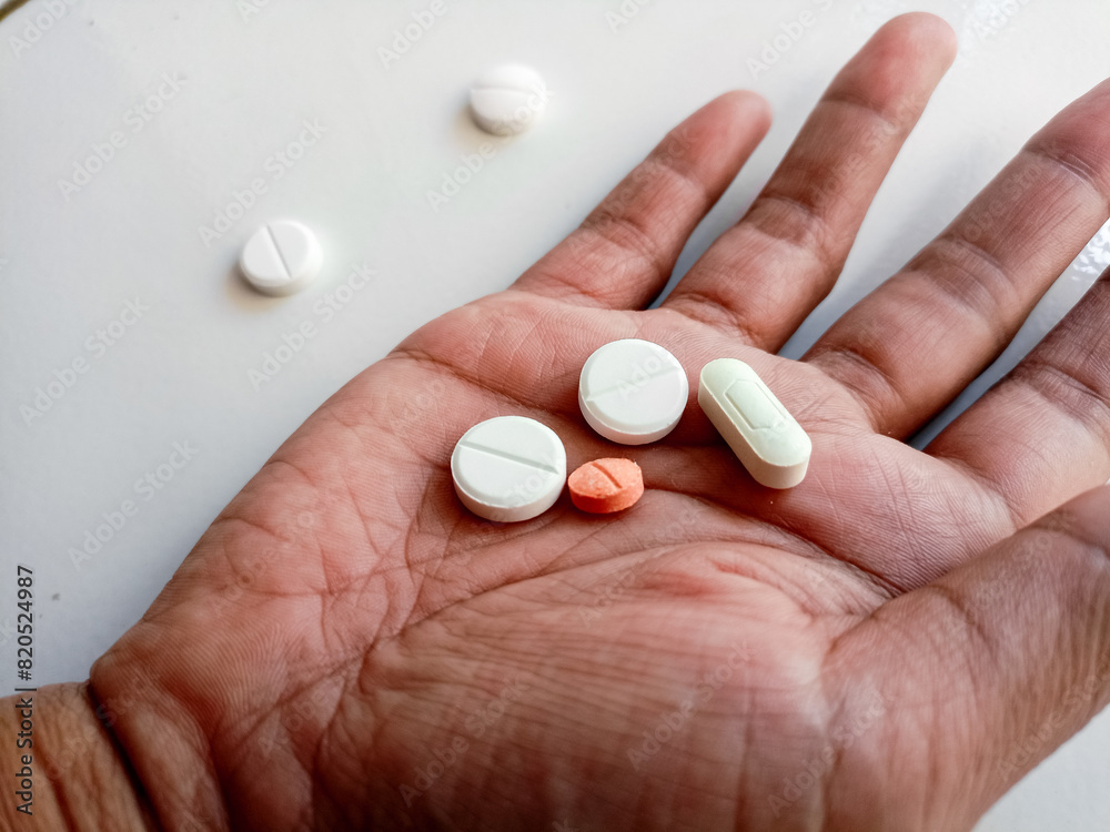 Asian Woman's hand lying next to scattered medicine on white background. Asian Woman's hand lying next to scattered medicine on white background.