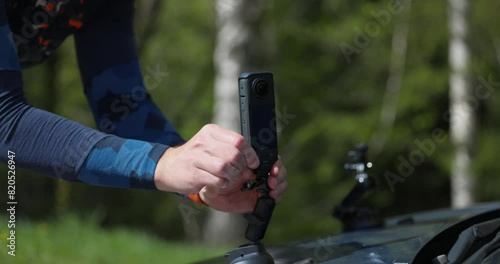 A Man's Hands Securing the Insta360 X4 to the Hood of a Car - Close Up photo