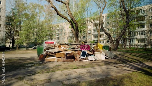 furniture, junk, electronics thrown on the ground near garbage bins in an Eastern European courtyard pov foward photo