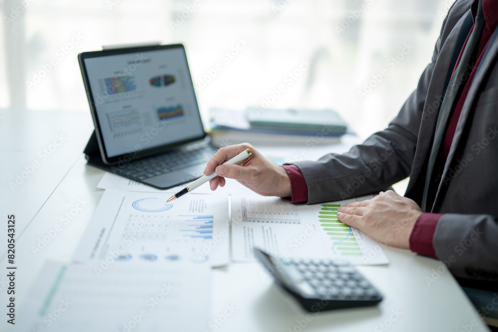 A man is sitting at a desk with a laptop and a calculator A man is sitting at a desk with a laptop and a calculator