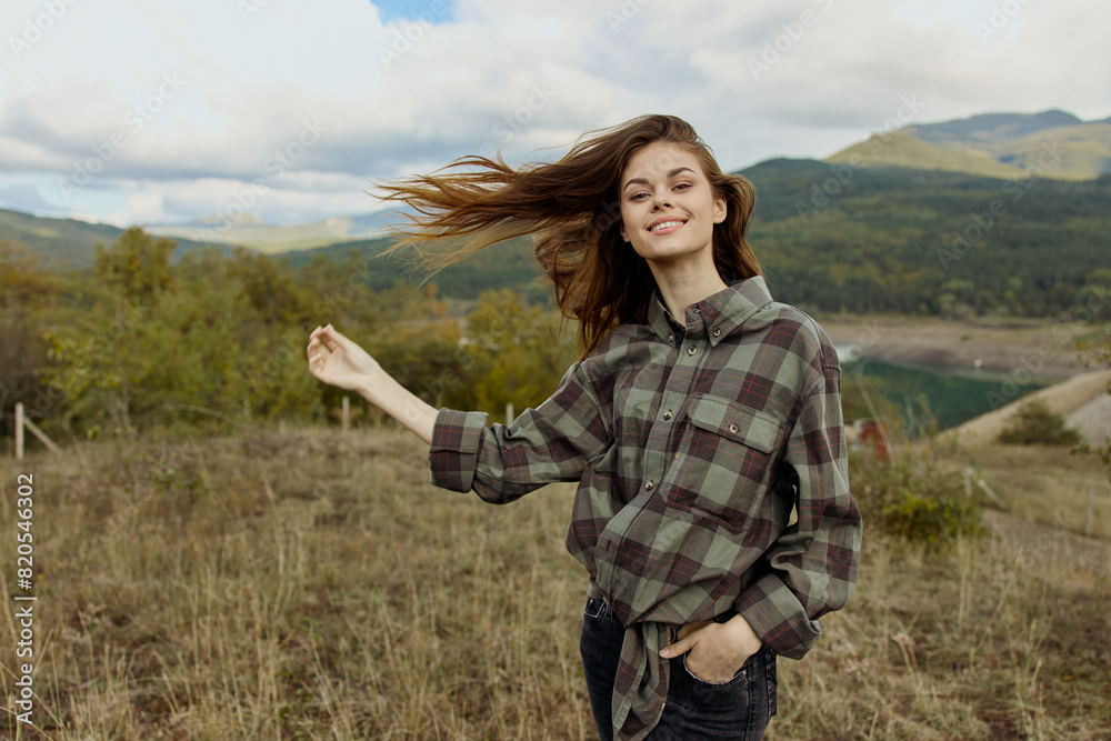 A woman in a plaid shirt standing gracefully in a windswept field, showcasing the beauty of nature and freedom A woman in a plaid shirt standing gracefully in a windswept field, showcasing the beauty of nature and freedom