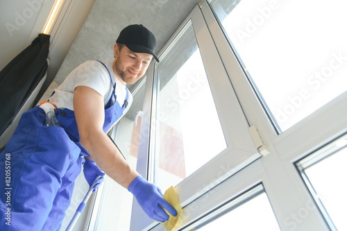 Cheerful male person cleaning window