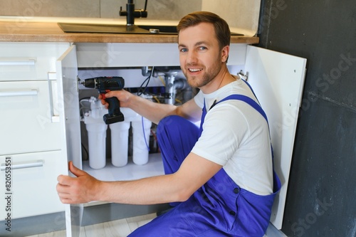 Plumber installs or change water filter. Replacement aqua filter. Repairman installing water filter cartridges in a kitchen. Installation of reverse osmosis water purification system. © Serhii