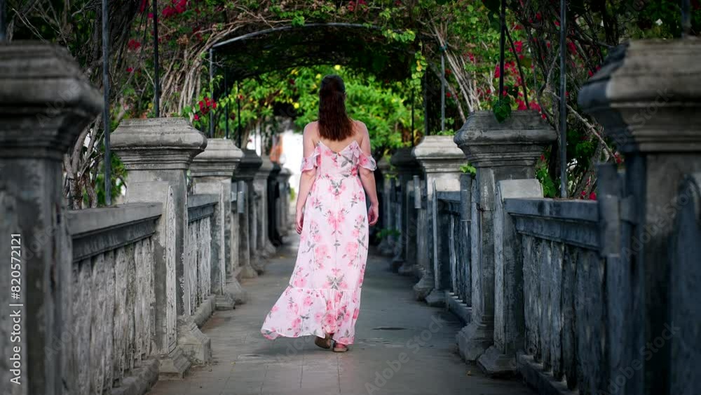 Female tourist in dress explores beautiful Ujung Water Palace in Bali, rear shot Female tourist in dress explores beautiful Ujung Water Palace in Bali, rear shot