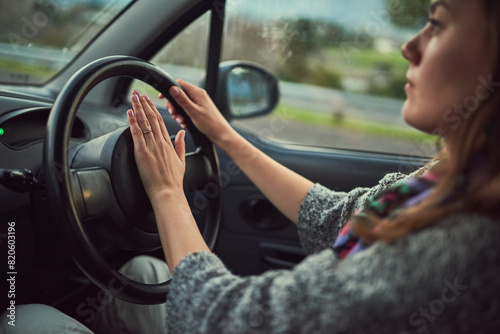 Woman, car and driving with honk on road for alert, emergency or traffic in travel, trip or transport. Female person hooting in vehicle with steering wheel for sound, horn or beep for incoming speed photo