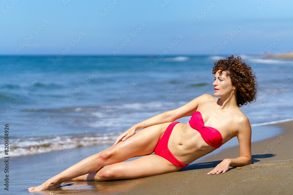 Slim woman in bikini suntanning on sandy beach Slim woman in bikini suntanning on sandy beach