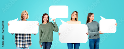 Four women holding empty speech bubbles standing against a turqu photo