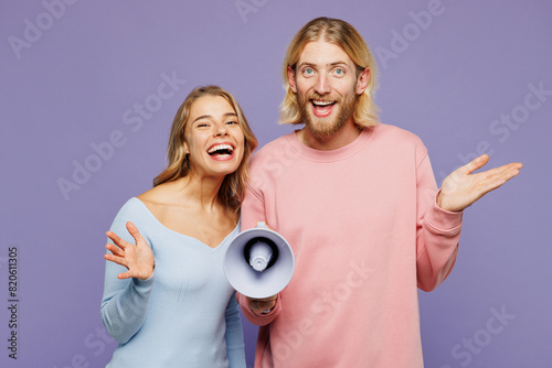 Young surprised shocked couple two friends family man woman wear pink blue casual clothes together hold megaphone scream announces discounts sale Hurry up isolated on pastel plain purple background.
