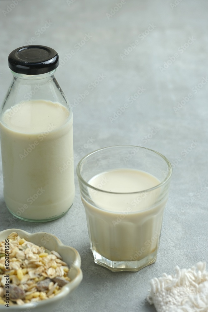 Milk in glass with gray background. Soymilk for breakfast. Muesli in back. Susu kedelai Milk in glass with gray background. Soymilk for breakfast. Muesli in back. Susu kedelai