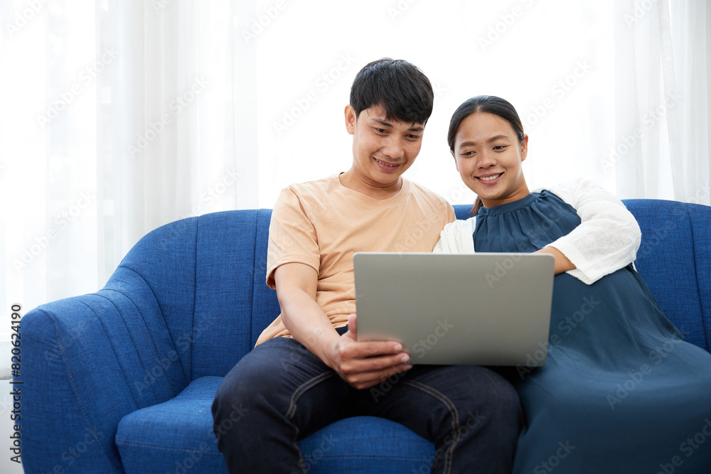 pregnant woman with her husband doing online shopping from laptop computer at home pregnant woman with her husband doing online shopping from laptop computer at home