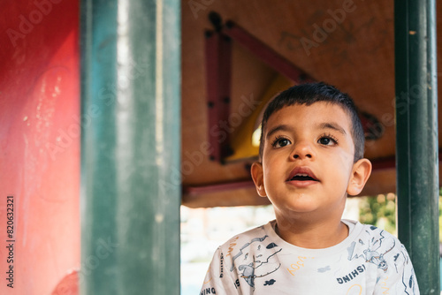 Autistic boy having his head in the clouds on playground. Joyful young boy using imagination while playing on colorful playground equipment