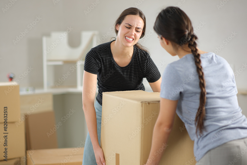 Two women suffering lifting box moving home Two women suffering lifting box moving home