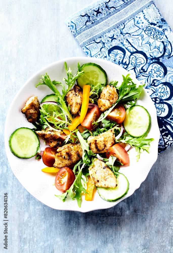 Healthy Salad with Grilled Chicken Briest, Cherry Tomatoes, Yellow Pepper, Cucumber and Endive. Bright wooden background. Top view Healthy Salad with Grilled Chicken Briest, Cherry Tomatoes, Yellow Pepper, Cucumber and Endive. Bright wooden background. Top view
