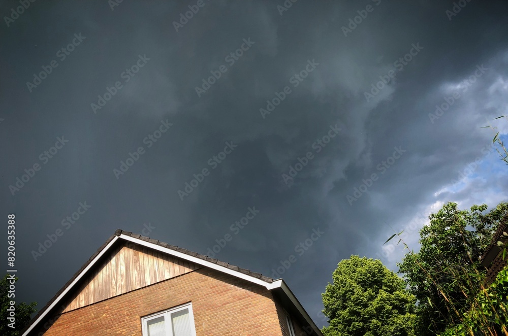 Thunderclouds packing together above a house in the Netherlands. Thunderstorm. Grey clouds.