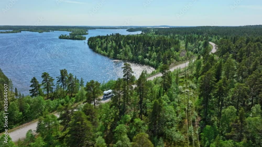 AERIAL: Motorhome driving on a distant road at lake Inari, summer day in Finland