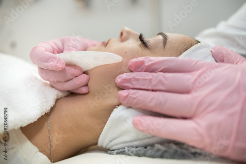 cosmetologist doing medical procedure with white gouache scraper on a client's face