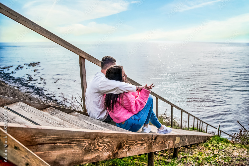 Naklejka premium Young married couple sitting on the wooden long stairs and looking at Japanese sea