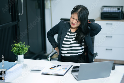 Businesswoman is doing a stretchy posture due to sitting in the office for too long, office syndrome concept. photo