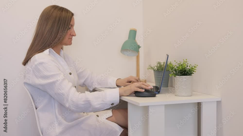 Woman works at desk with laptop, focused on her tasks. She types on laptop, checking emails and completing projects. Ideal footage for themes of productivity, remote work, and technology with laptop.